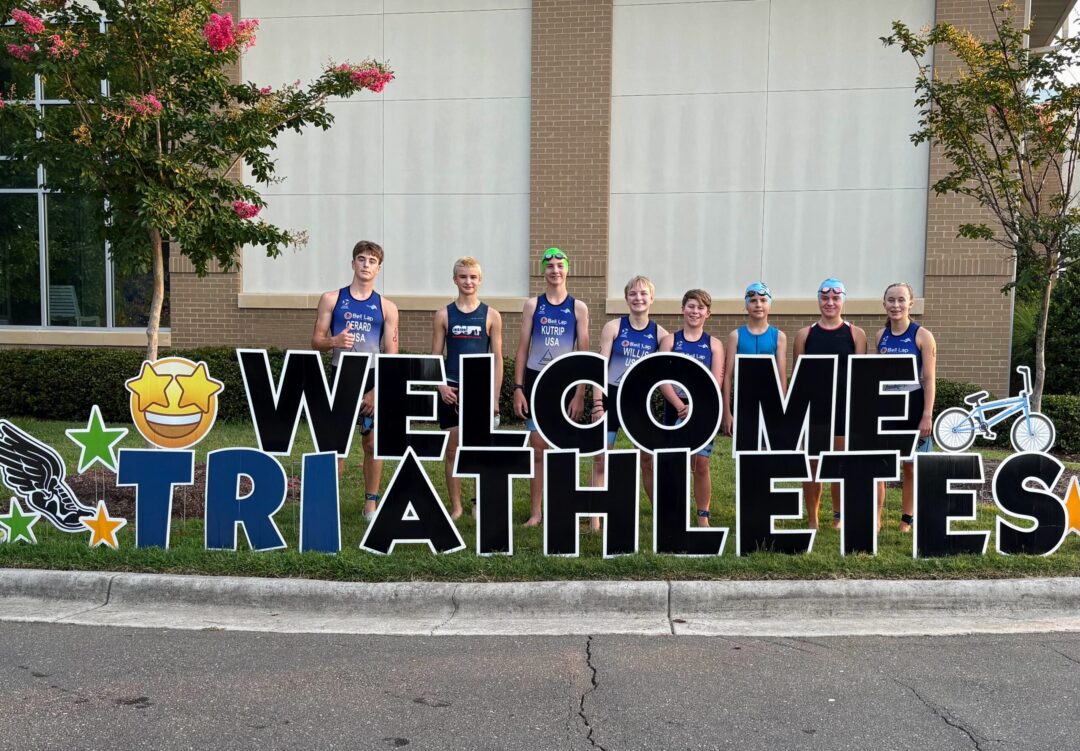 A group of Tenacity triathletes with a sign that says Welcome Triathletes